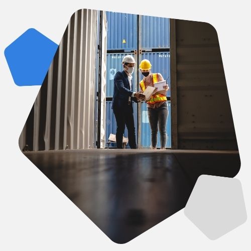 Two customs workers in hats looking into storage container