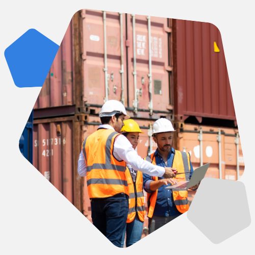 Men in high vis looking at sheet outside storage containers